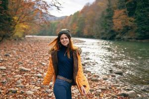 woman in a yellow jacket near the river in nature autumn travel photo