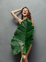 joyful woman hiding behind palm leaf nude body isolated background photo