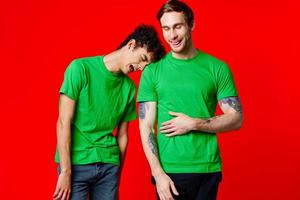 Two cheerful friends in green t-shirts are standing next to each other emotions isolated background photo