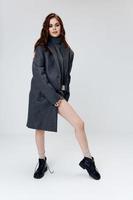 fashionable woman in coat shows naked leg and black boots photo