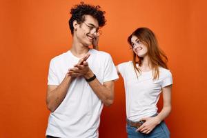 young couple in white t-shirts and glasses fun fashion orange background photo