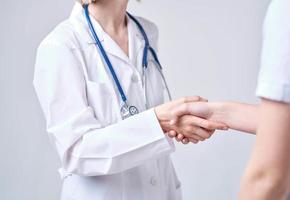 Professional doctor woman shakes hand of a female patient on a light background photo