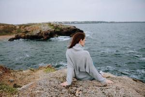 hermosa mujer suéteres nublado mar admirativo naturaleza estilo de vida foto