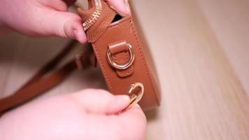 A woman's hand attaches a carabiner to a small bag video