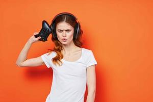 mujer en blanco camiseta vistiendo auriculares palanca de mando jugando naranja antecedentes foto