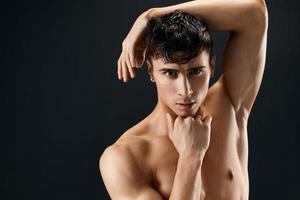 un atractivo hombre con un mejorado muscular cuerpo sostiene su mano en su cabeza de cerca foto