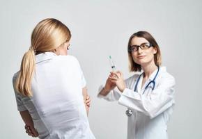 Frightened patient and nurse with a syringe in hand on a light background photo