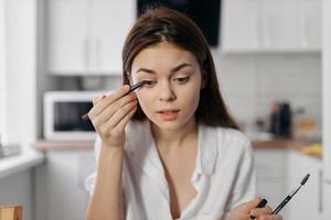 mujer en cocina haciendo maquillaje con delineador de ojos lápiz foto