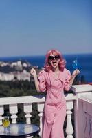 fashionable woman in a pink dress in sunglasses with a cocktail unaltered photo