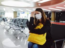 woman at the airport with medical mask waiting passenger yellow backpack photo