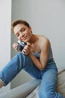 Woman photographer shooting in studio on old film camera at home on couch portrait, white background, free copy space, freelance photographer photo