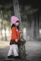 Portrait of cute asian little girl wear Winter clothes at the forest of the park,Thailand people pose for take a picture,Happy time photo