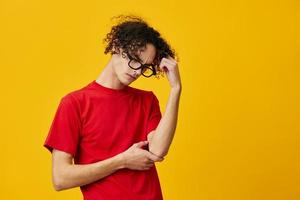 Pensive thoughtful myopic young student man in red t-shirt funny eyewear posing isolated on over yellow studio background. The best offer with free place for advertising. Education College concept photo