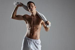 athletic guy with a pumped up torso wipes sweat with a towel around his neck photo