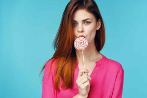 woman in pink shirt with lollipop in hands charm blue background photo