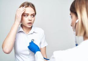 mujer paciente se queja de dolor de cabeza a médico con estetoscopio foto