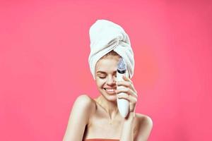 woman with bare shoulders with a towel on her head cleaning the skin photo