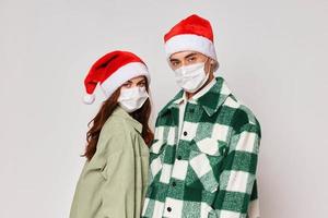 Man and woman in medical masks Christmas hats holiday gray background photo