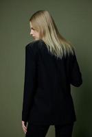 Elegant strict blonde girl turns her back to the camera looks away posing on a green background in the studio. The concept of advertising for designer brands photo