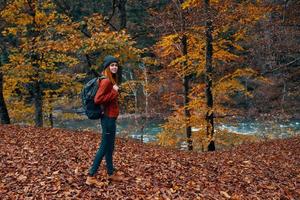 a traveler with a backpack walks in the park in nature near the river in autumn photo