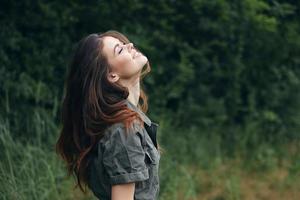 mujer en el bosque mirando arriba con cerrado ojos sonrisa libertad Fresco aire antecedentes naturaleza foto