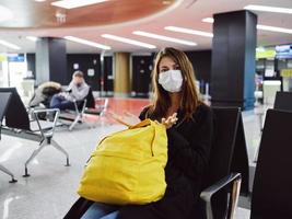 mujer vistiendo médico máscara amarillo mochila esperando aeropuerto pasajero foto