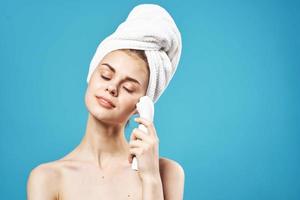 pretty woman with towel on head massaging face skin care photo