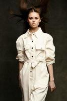 woman model posing on a dark background in white overalls and tousled hair on her head photo