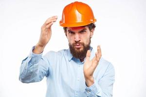 A man in a working uniform orange hard hat gestures with his hands emotions Construction engineer Professional photo