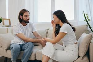 An Asian woman is sad and crying with her male friend at home. Stress and misunderstanding in a relationship between two people photo