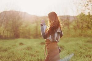 A woman running through a field on a summer day with long flowing hair in the rays of the setting sun. The concept of freedom and harmony with nature photo