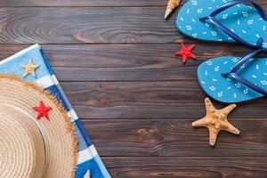 Straw hat, blue flip flops, towel and starfish On a dark wooden background. top view summer holiday concept with copy space photo