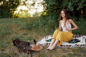 A hippie woman playing in nature with her little dog photo