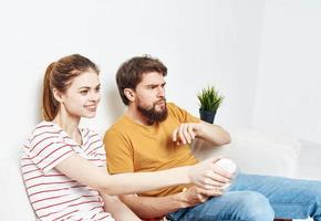 A man and a woman In a bright room sit on the couch with popcorn in a plate emotions friends green flower in a pot photo