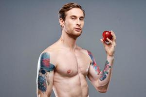 atlético hombre con un mejorado torso y un tatuaje en su brazo rojo manzana salud foto