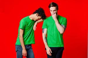 Two cheerful friends in green t-shirts joy of communication red background photo