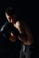 Boxer en negro guantes doblado abajo en un oscuro antecedentes carrocero foto