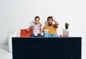 Watching TV married couple man and woman on the couch and a flower in a pot photo