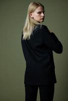 The blonde poses with her back to the camera. Concept photo for clothing brands. Cool offer for fashionable suits