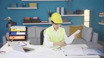 een grappig en opgewonden jongen ingenieur bochten zijn vader bureau ondersteboven omlaag. een jongen wie dromen van wezen een ingenieur rommelt en rotzooi omhoog zijn vader bureau. video