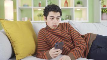 adolescente chico mensajes de texto en el teléfono se convierte aburrido, hosco, deprimido. un niño mensajes de texto y Hablando en el teléfono con perturbador y triste noticias. decepción. video