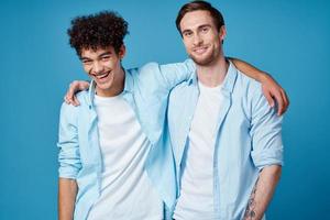 chico con Rizado pelo en un camisa y un camiseta en un azul antecedentes y un joven hombre amigos divertido foto