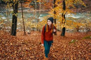 travel tourism woman in sweater and jeans in autumn forest near mountain river photo