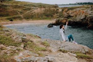 portrait of a woman seated on the coast sweater landscape female relaxing photo