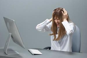 infeliz bonito rubia mujer de negocios trabajador toque cabeza ambos manos pensar de problema solución sentado a lugar de trabajo en gris moderno oficina. empleado trabajo en computadora en línea haciendo grande error. Copiar espacio foto