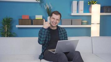 Happy and joyful man making check mark, ok sign looking at camera at home. Mature man using laptop at home happy and playful looking at camera making check mark. Arrow. video