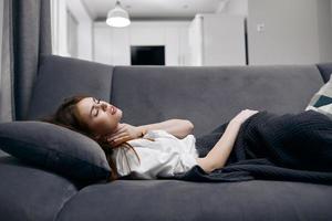 woman lies at home on the couch covered with a blanket health problems photo