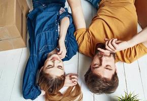 A woman-man with a flower in a pot lie on the floor In a bright room near the sofa photo