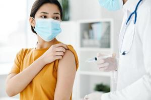 a patient in a hospital and a doctor in protective gloves inject a vaccine into the shoulder of a woman covid photo