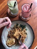 spaghetti bolognese hand in frame with drink photo